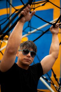 Colorful picture background of a sexy muscle man wearing sunglasses looking away holding from a rope