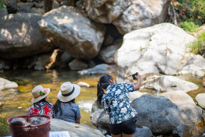 Rear view of people sitting on rock