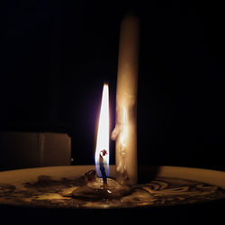 Close-up of lit candle in darkroom