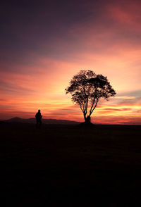 Silhouette man standing on field against sky during sunset