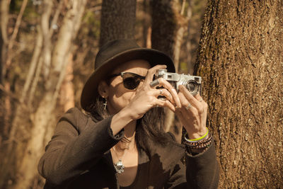 Woman photographing near tree trunk