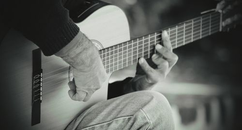 Midsection of man playing guitar