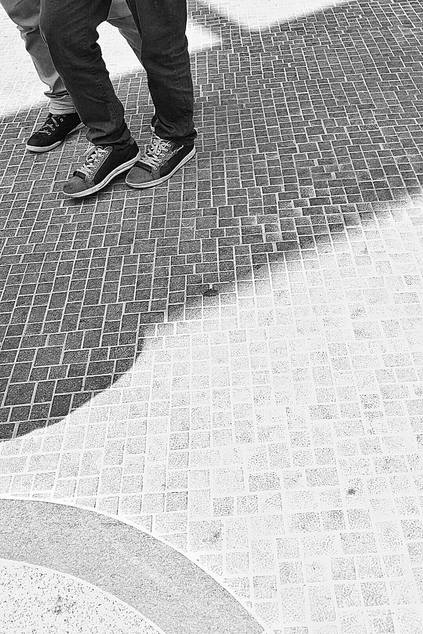 low section, person, lifestyles, leisure activity, high angle view, men, standing, street, shoe, pattern, unrecognizable person, human foot, shadow, walking, sunlight, outdoors