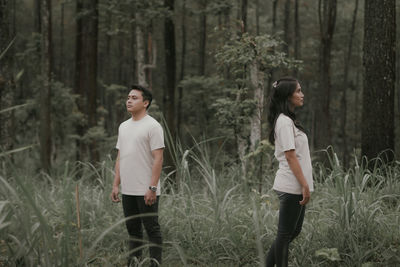 Side view of woman standing on field in forest