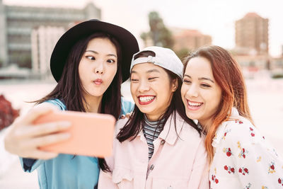 Cheerful friends taking selfie in city
