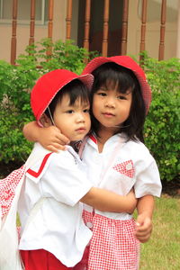 Portrait of girl embracing brother in yard