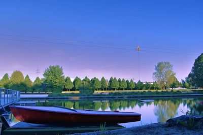 Reflection of trees in lake against clear blue sky