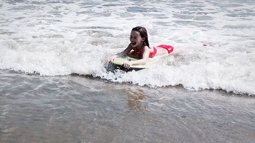 Portrait of smiling young woman holding water in sea