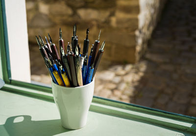 Colorful penholders with calligraphy nibs in mug on window sill
