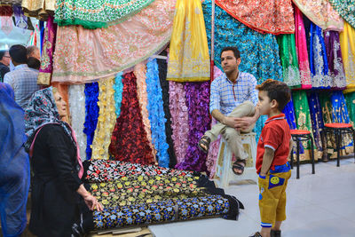 Full length of friends standing at multi colored umbrellas