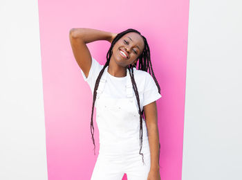 Portrait of young woman with arms crossed standing against white background