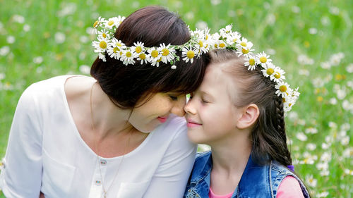 Summer, amidst a chamomile lawn, in the forest, a young woman, a brunette and a girl of seven