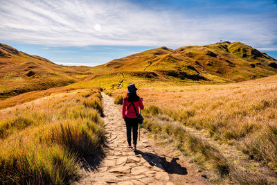 Rear view of woman walking on mountain against sky