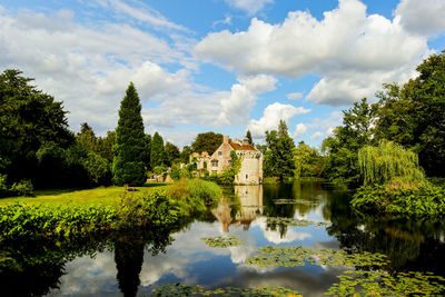 Scenic view of lake by trees and buildings against sky