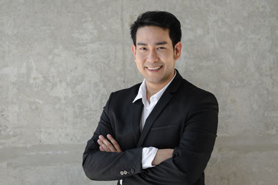 Portrait of smiling confident businessman standing against wall