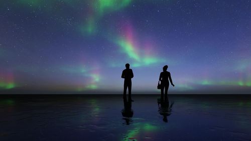 Rear view of silhouette friends standing against sky