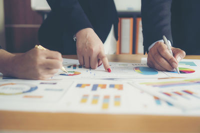 Close-up of businessman and colleague working over graph on table