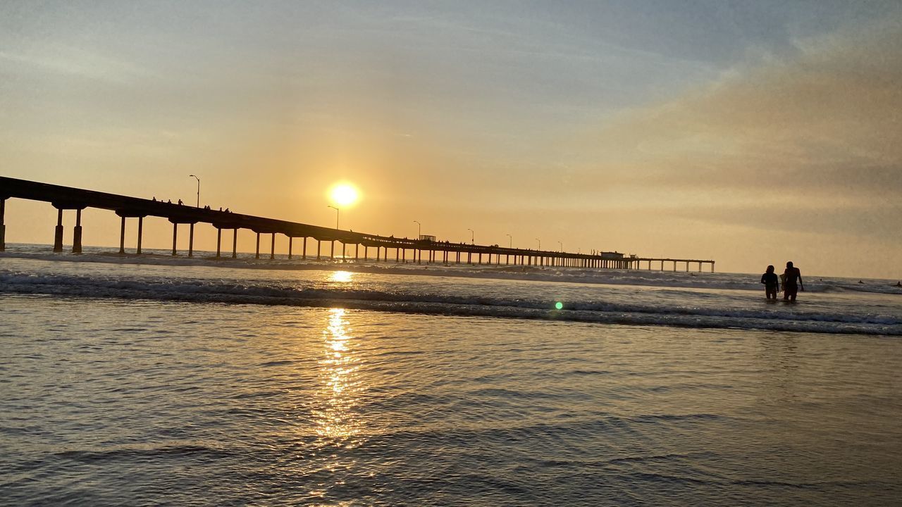 BRIDGE OVER SEA AGAINST ORANGE SKY