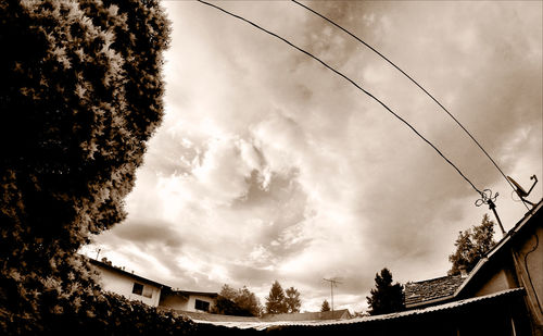 Low angle view of electricity pylon against cloudy sky