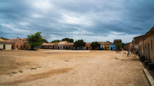 Houses by buildings in city against sky