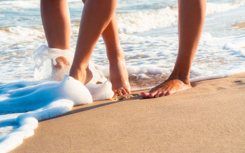 Low section of woman walking on shore