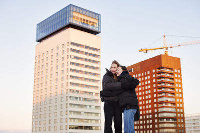 Female couple hugging in modern neighborhood