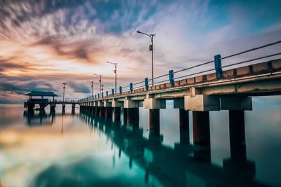 Pier over sea against sky during sunset