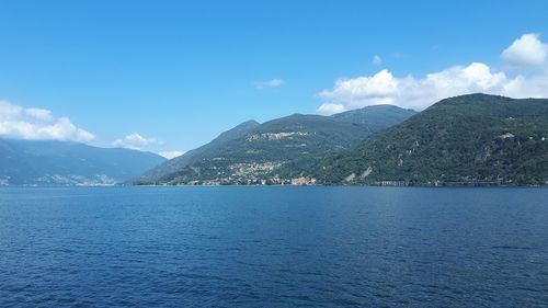 Scenic view of sea and mountains against blue sky