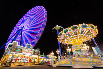 Low angle view of illuminated ferris wheel against sky at night