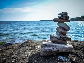 Stack of stones in sea against sky