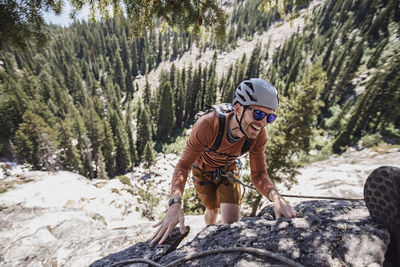 A young man smiles while rock climbing in the tetons, wyoming