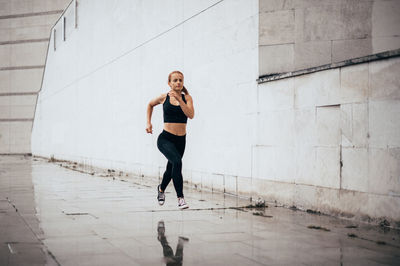 Full length of woman standing against wall