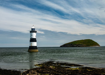 Lighthouse by sea against sky