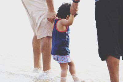 Two men and young boy standing in sea