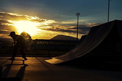 Silhouette man skating against sky during sunset