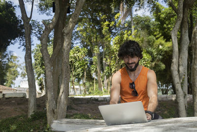Man at a park on a beautiful sunny day with laptop. notebook work and leisure. green and nature