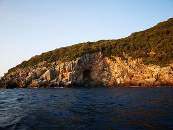 Rock formations by sea against clear sky