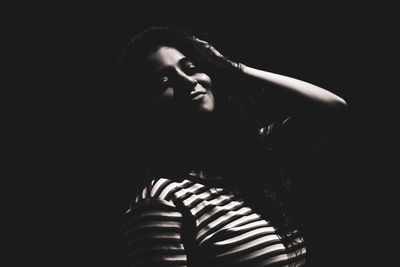 Portrait of young woman looking away against black background