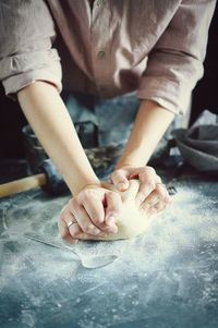 Midsection of woman kneading dough in kitchen