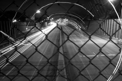 Light trails seen through metal fence at night