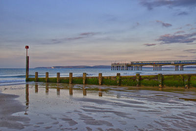 Wooden posts on beach against sky