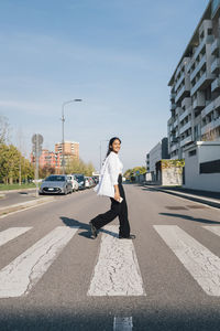 Young woman crossing road on sunny day