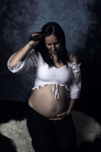 Beautiful young woman standing against black background