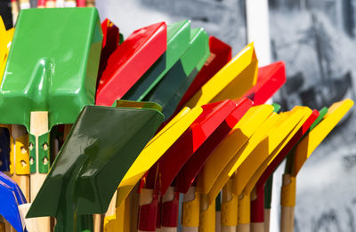 The photo shows several colorful children's shovels in the sun