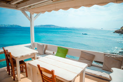 Chairs and table by swimming pool against sea