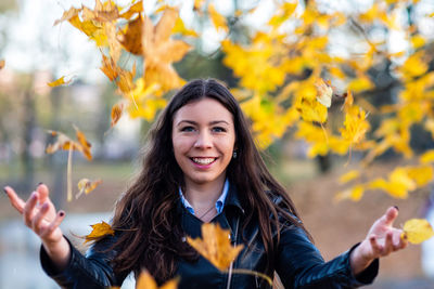Portrait of happy young woman with autumn leaves