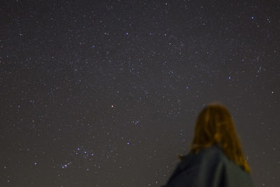 Low angle view of woman against star field at night