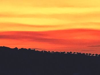 Scenic view of silhouette landscape against orange sky