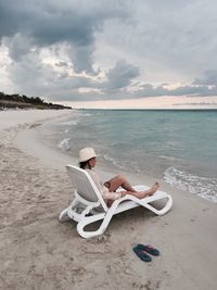 High angle view of woman sitting on deck chair at beach