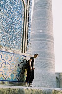 Low angle view of a man standing against kalyan minaret in bukhara uzbekistan 